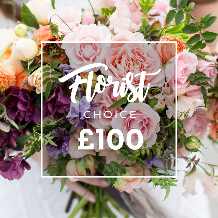 A lush, hand-tied bouquet fills the frame, artfully photographed with a white rectangular label over the centre reading Florist Choice in elegant script, CHOICE in block letters beneath, and a bold ?100 displayed at the base of the frame to indicate the price. The floral story is built around large, soft pink garden roses whose many ruffled petals suggest a peony-like fullness, counterbalanced by clusters of deep plum hellebores or similar textured blooms that add weight and dramatic colour. Delicate, striped sweet peas in pale lilac and white weave through the roses, lending a whimsical, airy quality, while peach and coral ranunculus-style blooms bring warmth and layered form. Little creamy white accent flowers highlight the colour shifts and break the composition into intimate vignettes. A generous mix of greenery - from slender, trailing vines to broader leaves reminiscent of eucalyptus - gives the bouquet a natural, garden-harvest look and a whisper of cool, green scent. Soft daylight sculpts the petals and casts gentle shadows, and at the bottom a pair of hands in a light sleeve hold the stems with calm care, as if just prepared for delivery to a nearby New Barnet High Street address or to be collected by someone after visiting the local market. This image projects artisanal quality and seasonal freshness, an expert florist's selection made for occasions from heartfelt thank-you gestures to elegant wedding bouquets.