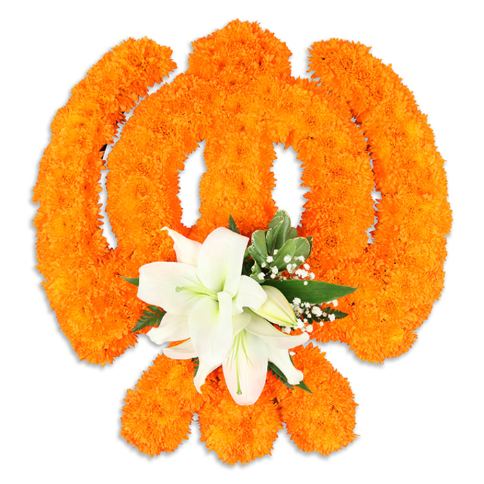 This floral composition interprets the Ik Onkar symbol with a traditional palette and meticulous floral technique: the character's vertical stroke, curving extensions and final dot are all shaped from a dense field of bright orange marigold blossoms, each bloom contributing to a textured, almost textile-like surface that gleams softly under studio light. The marigolds' clustered heads give the symbol a celebratory, tactile quality-warm, festival orange that carries cultural resonance in Sikh ritual. Nestled at the lower centre of the arrangement, where the form narrows, a cluster of pristine white lilies provides an elegant focal point: at least two open lilies with petals looping gently outward, showing subtle green and yellow stamens, accompanied by smaller lily buds that suggest continuity and hope. Glossy green foliage and delicate sprays of tiny white filler flowers, likely gypsophila, weave around the lilies, creating shadowed pockets and a cool counterbalance to the orange. A faint drop shadow beneath the piece hints at its freestanding construction, while the clean white background keeps the composition legible and solemn. The mood is devotional and refined, suited to Ik Onkar's message of unity and remembrance; it reads as a floral offering you might see at community gatherings or at a quiet home altar in New Barnet, assembled with local sensibilities in mind and reflecting the workmanship of a neighbourhood floral studio just off Station Road near New Barnet station. The visual invites reflection-colour, texture and form working together to convey faith, unity and the gentle fragrance of fresh blooms.