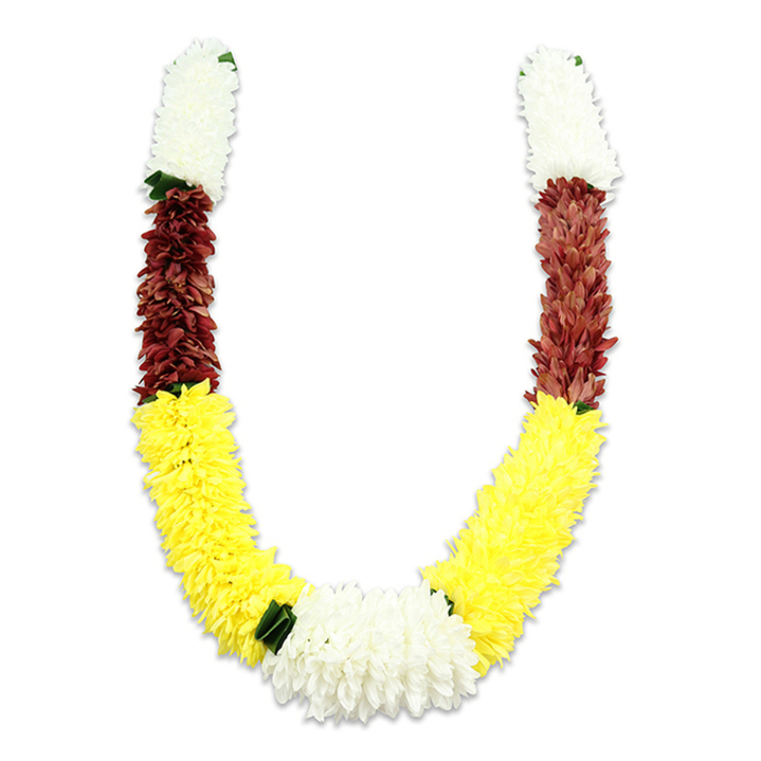 This vibrantly coloured mala, presented on a stark white background, shows the kind of careful construction we specialise in at Flowers New Barnet for local ceremonies and decorative use. The U-shaped garland is built from tightly clustered artificial blooms: each arm begins with a cylindrical section of creamy white flowers-small, dense petals shaped like miniature chrysanthemums-giving a clean, auspicious opening to the piece. Immediately below, a deep maroon or reddish-brown band of equally compact petals introduces a strong, dignified contrast before the design flows into the longest and most visually dominant portion: a broad expanse of bright yellow flowers, fashioned to mimic the fullness of marigolds and to create the warm, uplifting curve of the U. At the very base where the two yellow arcs meet, a substantial cluster of pure white chrysanthemum-like blooms forms a central focal point, wider and more luxuriant than the upper white tips. Tiny dark green leaf elements are placed at key transition points-notably where yellow yields to white-providing subtle punctuation and a natural break between colour blocks. Although made from fabric for durability in repeated puja use, temple offerings, weddings, and festivals across New Barnet-from Station Road gatherings to community halls near Oak Hill Park-the garland retains a soft, inviting appearance and showcases meticulous petal-by-petal craftsmanship suited to cultural rituals and home décor alike.