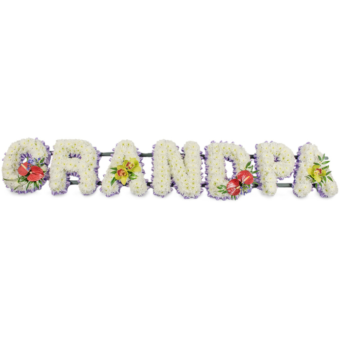 This image shows a striking GRANDPA funeral tribute arranged in a long horizontal line, the letters presented in bold block capitals against a plain white ground that makes every flower and ribbon edge clearly visible. Each individual letter is created from masses of small, pristine white chrysanthemums, packed closely so there are no gaps, just a soft, textured blanket of petals. The chrysanthemums' slightly domed heads form a gentle, cushioned surface, suggesting both purity and comfort, the sort of finish an experienced florist in New Barnet would take time to perfect. Running along the base of every letter is a subtle band of light lavender ribbon, the cool purple tone providing a quiet halo around the white and helping define the contours when the tribute is viewed from across a chapel or crematorium hall. Behind the blooms, dark green metal or wooden bars link the letters, giving the structure strength to sit on a stand or be carried with care to services in and around New Barnet and neighbouring areas like Oakleigh Park or East Barnet. Four letters are highlighted with richer colour: the 'G' and the 'D' carry generous sprays of deep red anthuriums, their waxy, heart-shaped blooms and bright central spadices framed with glossy green leaves and touches of delicate purple filler, representing love, courage, and warm memories. The first and last 'A' are softened with elegant clusters of yellow-green orchids, their graceful, exotic faces arranged among lush foliage, adding a note of refined beauty and hope. This bespoke GRANDPA arrangement is designed as a heartfelt memorial tribute, ideal for funerals, wakes, or graveside tributes in the local Barnet community, where families seek a personal way to honour a much-loved grandfather.