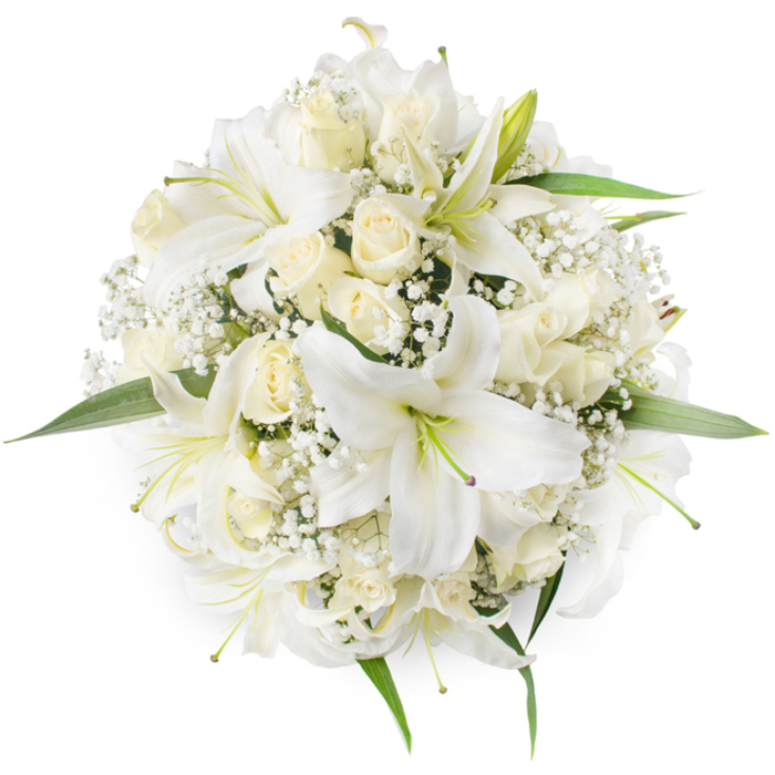 A meticulous overhead photograph reveals a compact, circular bouquet dominated by white lilies and soft cream roses, set against an immaculate white backdrop so every petal and texture is in sharp relief. The lilies are prominent, their wide, trumpet-like petals unfurling to expose pale greenish-yellow stamens that lend a subtle point of contrast within the otherwise monochrome scheme; their petal surfaces appear satiny under gentle, diffuse light. Intermingled are tightly furled and partially open cream roses, their layered, velveteen petals building small, intricate rosettes that offer a tactile counterpoint to the lilies' openness. Wisps of baby's breath (Gypsophila) thread through the arrangement like a delicate veil, softening transitions and filling the negative space with tiny, cloud-like clusters. Around the outer edge, fresh green foliage emerges sparingly, adding crispness and structure without disrupting the bouquet's serene palette. The balance of scale, texture, and scent - sweet, floral lilies tempered by the warm, honeyed note of roses - creates an impression of timeless elegance suitable for weddings, christenings, anniversaries, or reflective memorials. Imagine this bouquet resting on a windowsill near Lyonsdown Road or being placed on a reception table at a community celebration in Brunswick Park: it reads as both ceremonial and quietly local, the handiwork of an experienced florist who understands the understated tastes of New Barnet neighbours.