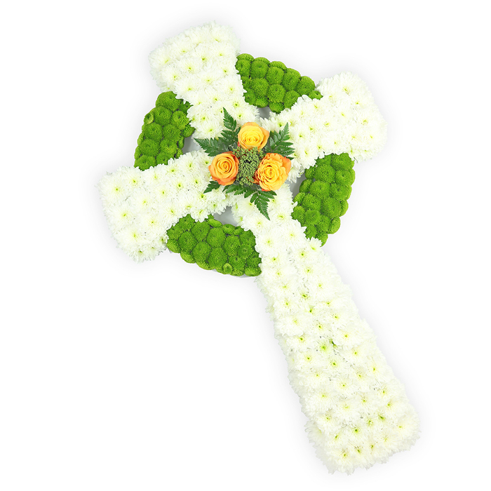 A three-dimensional Celtic cross of fresh flowers sits against a bright white backdrop, photographed from a slightly elevated viewpoint so the circular centre and elongated shaft are clearly visible. The cross's mass is worked entirely in small white spray chrysanthemums, closely grouped to produce a smooth, dignified surface that suggests purity and quiet devotion. Bright, almost lime apple-green button chrysanthemums are carefully inlaid to form the ring at the intersection of the arms and to mark alternating sections along the horizontal arms, the vivid green creating a plush, architectural banding that enhances the cross's traditional knot motif. At the precise centre, a focused cluster of three warm orange-yellow roses provides a vivid contrast; their glowing petals are framed by a few dark green fern sprigs which accentuate the roses' colour and add a natural, subdued scent. The composition is lit with soft, directional light that emphasizes the three-dimensional shaping and the delicate variations of petal texture without harsh shadows. The white, green, and orange palette also quietly evokes the Irish tricolour, making this composition particularly meaningful for services honouring Celtic heritage. As a tribute prepared by Flowers New Barnet for families across Oak Hill Park, Monken Hadley and the streets around Station Road, this cross communicates sympathy, reverence and a handcrafted attention to detail-appropriate for funeral chapels, memorial services, or a graveside farewell where the community gathers to remember.
