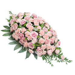 Displayed on a crisp white background, this elongated funeral spray forms a classic teardrop, full and rounded at the top left and narrowing to a gentle point at the lower right. The heart of the design is a dense sweep of soft pink roses, many fully open with velvety, spiralling petals, others slightly cupped as if just reaching their prime. Between them nestle pale peach-pink and blush carnations, their finely ruffled petals offering a soft, cushioned texture that contrasts with the smoothness of the roses. The flowers sit close together, creating a rich, almost quilted surface of pastel blooms. Around and beneath this mass of pinks, generous dark green foliage provides structure and contrast: broad, polished leaves form a steady base, while lighter, more delicate sprigs and tendrils of greenery extend from the sides and tip, giving the spray an organic, flowing outline. The colour palette is tender and understated-muted rose tones, whisper-soft peach, and fresh green-ideal for expressing quiet sympathy and remembrance. The arrangement is clearly designed to lie flat, suited to resting on a coffin, a graveside in New Barnet, or a memorial table in a local church off the Great North Road. The even lighting shows every detail of petal and leaf, highlighting the thoughtful craftsmanship. This floral tribute feels like a gentle embrace from family and friends in the New Barnet community, a respectful expression of support, love, and peaceful farewell.