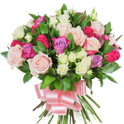 Viewed close-up against a brilliant white studio background, this dense bouquet of mixed roses reads like a small garden gathered and tied by hand. The composition showcases large, fully opened roses in dusky pastel pinks and creamy whites, their layered petals soft to the imagined touch. Interspersed are striking fuchsia-magenta roses that give the bouquet a lively, celebratory edge, accompanied by subtle lavender blooms that introduce a cool, restful accent. Nestled in the folds of the bigger flowers are sprays of tiny white and pale-yellow spray roses, which add delicate texture and visual rhythm. Dark green, glossy leaves-reminiscent of ruscus or salal-are tucked throughout, their smooth, elongated surfaces reflecting studio light and creating a vivid contrast that makes each blossom read brighter. The stems are gathered neatly and finished with a wide, satin baby-pink ribbon tied into a large bow; the ribbon's sheen and the bow's generous loops lend a polished, gift-ready look. As a florist who knows New Barnet well, I picture this bouquet carried from Station Road down toward Brunswick Park, its scent faintly rosy with a fresh green lift and its presence suited to birthdays, anniversaries, or a tender note of thanks. Prepared for local delivery by Flowers New Barnet, it reads as both joyful and refined-an arrangement that speaks of affection, celebration, and quiet elegance in a neighbourhood context.
