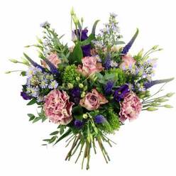 A rounded, luxuriant bouquet of fresh flowers is shown from a slightly overhead angle against a crisp white background, its colours and textures reminiscent of a calm spring evening in New Barnet. Loose spirals of pastel pink roses form the gentle core of the arrangement, some tightly budded, others more open, revealing delicate, layered centres touched with hints of deeper pink at their edges. Interwoven among them are generous carnations in shades of dusty rose and mauve, their ruffled petals spilling into one another and creating a soft, almost cloud-like volume. Rising gracefully through this softness are the elegant spires of indigo-violet Veronica, their slender forms adding height and a hint of wild meadow character. Tucked between the taller stems, velvety lisianthus blooms in rich purple lend a deeper note to the palette, balancing the lightness of the roses. Sprays of tiny lavender-blue, daisy-like flowers drift through the bouquet, each with a small, bright centre that catches the light, giving the whole piece a sense of movement and delicacy. Around the blossoms, varied foliage in lime green and silvery eucalyptus tones creates a lively yet soothing frame, echoing the greenery of nearby parks and tree-lined streets off East Barnet Road. The hand-tied stems are neatly gathered, clearly visible where they meet at the base, suggesting a bouquet ready to be placed in a favourite vase on a New Barnet kitchen table. The arrangement feels modern yet romantic, ideal for local flower delivery to mark a thoughtful milestone, a quiet celebration at home, or a comforting, heartfelt gesture to someone nearby.