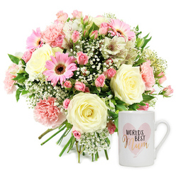 A warmly lit studio image presents a lovingly coordinated gift set, reminiscent of a thoughtful surprise delivered to a home off East Barnet Road in New Barnet. On the left, a generous, round bouquet of fresh flowers overflows with soft romance and cheerful colour. Cream roses sit at the heart of the design, their layered petals gently unfurling, while blush pink carnations with frilled edges nestle closely beside them. Bright pink gerbera daisies, each with a deep brown central disk, bring a playful, modern note, their broad petals radiating outward like little sunbursts. Threaded throughout, loose sprays of white baby's breath add a misty, cloud-like softness, and elegant white alstroemeria with fine reddish speckles offer long, graceful petals that stretch delicately from the centre. Hints of glossy green foliage peek between the blooms, adding depth and a freshly-cut garden feel, as though the flowers had just arrived from a nearby New Barnet market. The stems are bound together at the base in a classic hand-tied style, with the cut ends neatly aligned and slightly visible below the flower heads. To the right, a white ceramic mug stands upright, its surface smooth and simple, the perfect canvas for a loving message. A pale watercolour pink heart is painted on the front, and within it, WORLD'S BEST appears in a neat black typeface, sitting above the word Mum, written in flowing metallic gold or rose-gold script that catches the light. Together, the fragrant bouquet and sentimental mug create a scene of homely comfort and appreciation, ideal for honouring a mum on Mother's Day, her birthday, or any moment when you want to send a heartfelt thank you in New Barnet.
