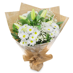 An elegant hand-crafted bouquet is shown upright against a clean white backdrop, allowing every detail of its white and green flowers to stand out with serene clarity. Large daisy-like chrysanthemums in pure white form the main body of the arrangement, each blossom composed of layered petals and centred with a soft yellow-green disc that adds a note of gentle cheer. They are nestled closely together, creating a generous cushion of bloom that feels both comforting and fresh, like opening the door of a calm New Barnet home after a walk along East Barnet Road on a bright day. Rising gracefully through this cushion are several tall lily buds, still closed, their slim, pale green forms ending in creamy white tips. These buds add structure and height, suggesting a sense of unfolding hope, as though the bouquet will continue to evolve in the days after it is delivered. Delicate sprays of white baby's breath are interlaced throughout, adding a misty, ethereal texture around the central flowers. The entire design is framed by glossy green foliage, the leaves rich and verdant, echoing the well-tended gardens and tree-lined streets around New Barnet. An inner wrapping of brown kraft paper brings warmth and an organic feel, its slightly rumpled texture suggesting the careful touch of a local florist, while a clear cellophane outer layer catches the light with a soft shine and keeps the stems secure. Gathered and tied neatly at the base, the bouquet has a poised, ready-to-gift appearance. It conveys an atmosphere of tranquillity and remembrance, making it a thoughtful choice for sympathy tributes, hospital visits, or quiet reflection at home in the New Barnet area.