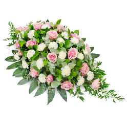 Displayed on a pure white background, this elongated teardrop funeral spray feels like a gentle gesture of farewell, the sort of thoughtful tribute you might see carried into a New Barnet service on a still morning. The arrangement curves gracefully from a full, rounded top left down to a fine, tapering point at the bottom right, creating a flowing silhouette that echoes the shape of a single falling tear. Soft pink roses dominate the design, their petals unfolding in layered spirals, ranging from delicate blush tones to richer, romantic rose pink. Some blooms are in full splendour, while others are partially opened, hinting at the transient beauty of life. Nestled among them, ruffled white carnations and smaller spray carnations bring a cloud-like softness and bright contrast, their textures adding depth without overwhelming the gentle colour palette. Beneath and between the flowers sits an abundance of lush foliage: glossy dark green leaves, probably salal or camellia, give the piece structure and richness, while rounded eucalyptus leaves in a calm silvery green introduce a cooler tone and a subtle, soothing scent. From the slimmer end of the spray, fine strands of trailing greenery cascade outward, adding graceful movement and a natural finish. The even, neutral lighting ensures every petal, leaf, and curve of the design is clearly visible, emphasising the care of an experienced florist. This arrangement expresses sympathy, peace, and enduring affection, making it a fitting tribute for services in and around New Barnet, whether placed on a casket, at the front of a chapel, or beside a memorial photograph.