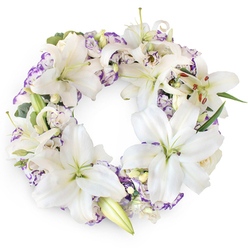 Set against a spotless white backdrop, this elegant circular wreath forms a continuous halo of white and soft purple, a refined tribute that feels both comforting and composed. The design is dominated by luxurious Oriental lilies in purest white, each bloom opening wide to show a soft, greenish-yellow centre and tall stamens lightly tipped with rust-coloured pollen. Their broad, velvety petals overlap and cradle one another, creating a sense of embrace. Nestled between the lilies are clusters of lisianthus, with delicate white petals fringed in lavender and richer violet tones, their ruffled edges adding movement and a whisper of colour, as if echoing the muted hues of an evening sky over New Barnet's quiet streets. A scattering of unopened lily buds and perhaps a few shy rosebuds, still creamy and tight, hint at life continuing, even in moments of farewell. Subtle greenery, from slim, tapering leaves to small, rounded sprigs, threads through the wreath, offering structure and a gentle woodland freshness without disturbing the lightness of the arrangement. The image captures the wreath as a complete, unbroken ring, a classic symbol of eternity and the ongoing bond with a loved one who has passed. It feels perfectly suited to rest beside a coffin or stand at a memorial service in New Barnet or the surrounding neighbourhoods, where families gather to remember and say goodbye. Every detail in the wreath's composition conveys thoughtfulness, restraint, and respect, offering a soft, floral expression of condolence and hope.
