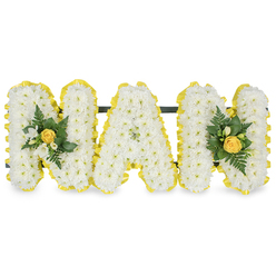 This tender floral tribute, imagined and prepared by a local hand, spells the letters M A M in three substantial capital forms, each densely covered in small, pristine white chrysanthemum sprays that create a soft, pillow-like surface. The perimeter of every letter is wrapped with a bright, pleated yellow satin ribbon that acts as a sunlit frame, giving a neat, cheerful edge and a refined contrast against the white blooms. To the left and right extremes the first and final M are enhanced with delicate accent clusters: each cluster centres on a soft yellow rose bud, its petals still gently furled, and is surrounded by tiny white freesia or similar bell-like buds and an assortment of deep green foliage including slender fern fronds and glossy leaves to deepen the colour palette. A sturdy, unobtrusive dark green or black bar runs behind the letters' upper sections to stabilise and link them for upright display, suggesting a memorial easel use or a graveside resting position. Set against a pure white background, the arrangement reads as both dignified and comforting; it radiates warmth without excess, purity without austerity. At Flowers New Barnet we craft tributes like this for families across New Barnet and nearby Brunswick Park and Barnet High Street, where the gentle yellow notes often remind people of shared afternoon teas and quiet summer sun; the scent is faintly sweet from freesia, and the tactile softness invites a moment of close remembrance.