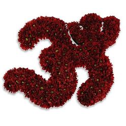 An elegant, hand-built floral number 33, composed entirely of small deep-red button chrysanthemums or closely related asters, occupies this image with quiet confidence. Each of the two numerals is formed by hundreds of tiny blooms, their petals layered into a lush, velvety crimson surface that catches light with a soft sheen. Scattered green centers and thin sprigs of greenery break the red gently, introducing a natural contrast that reads like tiny jewels across the composition. The arrangement rests against a pure white field, a choice that heightens the colour and throws a soft, diffused gray shadow beneath the 33, giving the impression of slight elevation and three-dimensional presence. The workmanship is deliberate and intimate, the kind of careful massing we create for milestone occasions: a 33rd birthday, a meaningful anniversary, a jersey tribute, or even a respectful memorial. As a local florist in New Barnet, I imagine this piece leaving our shop for delivery across Station Road and Brunswick Park toward Hadley Green, its compact, dense texture travelling well in cool boxes to preserve fresh petals. The visual language here is both celebratory and composed - a dignified flourish in deep crimson that reads equally as festive statement and considered homage, depending on the context in which it is used.