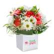 Radiating a sense of cheerful elegance, this lush bouquet pairs perfectly with the charm of New Barnet, echoing the vitality of nearby parks and leafy avenues. Crisp, white daisies with golden-green centers beam beside lush coral and peach carnations-their petals soft, ruffled, and inviting-together capturing the carefree brightness of a spring day in the neighbourhood. Baby's breath drifts through the arrangement, its miniature white blossoms adding a sense of lightness and childlike joy, while deep green foliage wraps the flowers in a glossy embrace. Subdued purple buds peek from the left, offering a hint of discovery and whimsical detail. Every flower is thoughtfully placed, forming a rounded composition bursting with texture and life, all presented in a spotless white square gift bag with ribbon handles sturdy enough for easy delivery to any address, from Brunswick Park to East Barnet. The professional white backdrop emphasizes freshness and quality, letting the colours and forms sing out-this bouquet, so expertly crafted, is sure to bring a lift to a birthday, congratulations, or any day that could use a flourish of local beauty. It's a floral embrace, delivered with love from the heart of New Barnet.