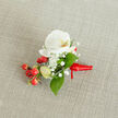 A close-up, overhead photograph of an elegant buttonhole arrangement resting on a softly textured, light oatmeal linen fabric, the sort of natural background you might see on a rustic wedding table in New Barnet. At the heart of the piece sits a pristine white Phalaenopsis orchid bloom, its broad petals gently curving outward like porcelain wings. The orchid's centre glows with a subtle wash of creamy yellow and warm orange in the throat, lending a quiet radiance and depth to the blossom. Encircling this focal flower are clouds of tiny white Gypsophila, or baby's breath, their airy clusters creating a delicate halo that contrasts with the orchid's smooth, satiny surface. Tucked neatly beside them is a compact spray of glossy, round red berries, reminiscent of hypericum, providing a cheerful, almost festive burst of colour that hints at winter celebrations or Christmas weddings held near Hadley Green or around the High Road. A few paler green, oval berry buds nestle nearby, suggesting new growth and freshness. Lush green foliage, some leaves broad and gently pointed, others narrower and more elongated, weaves between blooms and berries to ground the design in rich, natural tones. The stems are carefully bound at the base with a vivid red satin ribbon, wrapped snugly and tied in a small, tidy knot with short trailing ends, clearly ready to be pinned to a groom's lapel or the cuff of a prom outfit. The soft, even daylight across the fabric and flowers highlights every texture and detail, conveying a mood of calm anticipation and refined celebration, as if this small corsage were waiting in a New Barnet hallway just before guests step out to a wedding, formal dinner, or festive party.