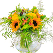 This radiant bouquet, crafted by the caring hands of local florists in New Barnet, shines with the golden energy of a high summer's afternoon in Oakleigh Park. The bouquet's focal point-two commanding sunflowers-beckon with joyful, wide faces, their lively yellow petals blazing against velvet-dark centres, reminiscent of sunlight spilling across Barnet playing fields. Pillowy clusters of yellow filler florets, likely solidago, nestle around the sunflowers, offering a dappled texture that mimics the wildflowers found along Station Road's garden borders. Delicate coral-orange blossoms peep out from among the greens, providing gentle warmth and a playful hint of colour, as if they've gathered the glow of New Barnet sunsets. Fern fronds delicately fan out around the arrangement, their layered greenery creating depth and an air of gentle wildness. Sprigs of steel-blue eucalyptus add a whispered freshness, while punchy lime-green leaves bring a bright, contemporary twist. All stems appear gathered tightly in a clear round vase, their lines softened by refracted light that conjures the clarity of a morning walk through Ravenscroft Park. The overall impression is one of cheerful abundance, optimism, and natural grace-an arrangement well-suited for celebrations, tokens of encouragement, or for lighting up any New Barnet home with a touch of floral sunshine, available for timely delivery from Flowers New Barnet throughout the local neighbourhoods.