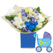 A soft, lullaby-like celebration captured in a single gift: a full, rounded bouquet of white roses, fragrant white lilies with a few buds still closed, and fluffy white chrysanthemums, accented by electric blue chrysanthemums and clusters of pale lavender-blue hyacinth-like florets. The blooms spill generously from a matte royal blue rectangular box, their petals catching a gentle, diffuse morning light that gives the whites a creamy, warm tone while the blues read as cool and vivid. Deep green foliage - broad, glossy leaves and fine ferny fronds - threads through the composition, adding depth and a quiet, garden-fresh scent that mingles with the sweet, green perfume of hyacinth and the honeyed hint of roses. The arrangement is wrapped at its base in crinkled cream tissue, the paper rustling softly when handled, making the unwrapping feel like a small, tender ceremony. To the right, a light blue foil baby-carriage balloon floats slightly above the box; its canopy and wheels are trimmed in darker blue with tiny polka dots and heart motifs, and playful yellow-green lettering reads Its a Boy, announcing the occasion with cheerful clarity. This bouquet feels handcrafted for welcoming a newborn son - gentle, joyful, and imminently giftable - suitable for a hospital visit, a baby shower, or to be left on the doorstep of new parents near New Barnet Station or Oak Hill Park. The overall impression is one of careful florist craft: balanced colour, varied texture, and a heartfelt message wrapped in comforting tones and fresh scent.