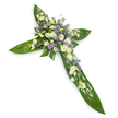 A solemn, elegant floral cross photographed on a clean white background from a gentle overhead angle, its simple silhouette isolated for quiet focus. The structural base is formed from broad, glossy tropical leaves - think Ti-leaf style foliage with visible veins and a smooth, waxy sheen - arranged to define the vertical and horizontal arms of the Christian cross. At the centre and running along each arm sits a generous cluster of pale blooms: ruffled, creamy-white lisianthus with soft, layered petals and unopened buds, rounded white chrysanthemum or daisy-like spray flowers that lend brightness, and delicate sprays of powdery lavender or pale purple aster/limonium that peek through like confetti. Fine, subtle sprigs of delicate green filler weave between the blossoms, adding softness and natural depth without obscuring the cruciform shape. The lighting is even and cool, smoothing shadows and enhancing the contrast between the luminous whites, soft lavenders and the deep verdant green of the leaves. Texturally the piece balances the smooth waxiness of the leaves with the airy, petaled softness of the lisianthus and the feathery tips of the tiny purple accents, while the scent would read as faintly green and floral - a restrained, comforting note rather than perfume. This arrangement reads as a dignified sympathy tribute suited to memorial or funeral settings, a visual expression of peace and remembrance often chosen for church services, chapel displays, or graveside placement in and around New Barnet, including quiet corners near Monken Hadley Common and Barnet High Street.