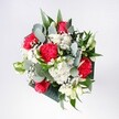 A lush hand-tied bouquet viewed from above, filled with crimson roses, pink-red carnations, and fluffy white chrysanthemums, arranged in a natural dome that looks as if it has just been set down on a sunny New Barnet kitchen table. The roses sit proudly at the heart of the design, their velvety petals spiralling outwards in deep, romantic red, while the carnations echo that passion with ruffled, almost feathery heads in vivid pinkish scarlet. Around them, daisy-like white chrysanthemums and tiny clustered daisies introduce a bright, cloudlike softness, each small petal catching the light like morning sun over Victoria Park. Wisps of gypsophila weave between the larger blooms, their miniature white flowers creating a fine, misty veil that lightens the whole composition. Threaded through the bouquet are long, cool eucalyptus stems and glossy tropical greenery, their grey-green and rich emerald tones shaping a calm framework that makes the reds and whites appear even more vibrant. The leaves vary in texture from smooth and waxy to delicately matte, adding depth and movement as they arch and curl around the flowers. The bouquet feels joyful yet composed, ideal for a birthday gathering in a New Barnet living room, a welcome-home surprise after a commute from central London, or a simple way to brighten a quiet corner near High Barnet station. It conveys the feeling of early spring and heartfelt affection, as if the florist has captured a bright, hopeful morning and tied it carefully with ribbon, ready for same-day delivery across the local streets and leafy avenues.