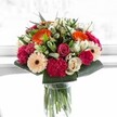 Looking at this bouquet, one senses a moment of pure happiness suspended in time-vivid orange gerberas radiate light and warmth, balanced exquisitely by the gentle blush of pink roses and the plush velvet of magenta carnations. Creamy ivory roses and soft peach gerbera tones deliver a touch of refinement, lending the whole ensemble a mood of quiet elegance and heartfelt tenderness. Bold, glossy greens frame the bouquet like the hedgerows lining leafy avenues of New Barnet, supporting each bloom and providing lush contrast. The light is bright, almost ethereal, revealing details such as the veins threading through petals and the softness of each curve. This is a bouquet to commemorate life's joyful milestones-an anniversary near New Barnet station, or a gift to brighten a friend's day in East Barnet Village. More than just flowers, this arrangement feels like a burst of community spirit brought to life by a local expert's careful hand, inviting the recipient into a vivid celebration of beauty, harmony, and heartfelt connection.
