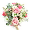 A chic blush pink hatbox brimming with flowers sits against a bright white background, its rounded shape echoing the domed bouquet of pink, white, and green rising above it. The box itself is a gentle, powdery pink, cinched with a slim reddish-pink satin ribbon and finished with a dangling cream tag that hints at a personal message, as if it has just been delivered to a doorstep off Lyonsdown Road in New Barnet. From the top, viewed slightly from above, a cluster of large light pink roses immediately draws attention; their petals curl inward in soft spirals, with some blooms fully open and others just beginning to unfurl, giving the arrangement a sense of life and progression. Between these romantic roses, neat white daisy-like chrysanthemums with vivid green centres bring crisp brightness and a sense of optimism, like sunlight breaking through clouds. White alstroemerias, with their fine purplish-red flecks and streaks along the inner petals, add delicate complexity and a whisper of the exotic, quietly supporting the central roses. The whole composition is wrapped in lush greenery: rounded, silvery eucalyptus leaves with a slightly matte finish create a cool-toned backdrop, while darker green, strap-like foliage peeks out to frame the blooms and extend the silhouette. Tiny clusters of reddish-brown buds or berries are tucked among the leaves, reinforcing the natural, garden-style character. The bouquet feels graceful yet approachable, ideal for birthdays, anniversaries, or simple gestures of kindness, and perfectly suited to be placed straight on a coffee table or bedside in any New Barnet home.