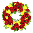 This image shows a generously filled circular funeral wreath, photographed against a pure white background so the colours appear vibrant and undistracted. The wreath is composed of a harmonious blend of deep red roses and bright yellow chrysanthemums, arranged tightly together to form a continuous, unbroken ring of blooms. The roses, in shades from classic scarlet to deeper burgundy, are fully open and carefully spaced, their velvety petals gently overlapping in layered spirals that suggest tenderness and devotion. Between and around them sit clusters of small yellow chrysanthemums, their countless fine petals giving each bloom a fluffy, almost cushion-like appearance that softens the overall texture. Lush green foliage threads through the flowers, adding volume and a sense of freshness, with some leaves glossy and dark, likely salal or similar greenery, and others paler and more matte, reminiscent of eucalyptus. The foliage provides a natural backdrop that frames the red and yellow flowers, enhancing their colour without competing for attention. The lighting is clear and even, allowing the viewer to appreciate every contour of the petals and subtle tonal shift in the greens. The central opening in the wreath is neatly defined, underscoring its symbolism of eternity and ongoing remembrance. This type of arrangement would be a familiar sight at funeral chapels, crematoriums, or gravesides in New Barnet, reflecting a thoughtful choice for families wishing to express love, sympathy, and respect. The overall mood is one of solemn beauty, a carefully composed floral tribute that honours a life while bringing a touch of colour and comfort to a difficult moment.