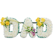 A tender, three-dimensional memorial spelled in large freestanding capital letters that read DAD, each letter hand-built from a dense carpet of pristine white spray chrysanthemums that give the forms a soft, pillowy texture. The crisp silhouette of each rounded letter is neatly framed with a ruffled dark green satin ribbon that traces both outer and inner edges, the deep green providing a steady, comforting contrast to the pure white faces. Behind the letters slim, dark green metal bars run horizontally, visible through the blooms, forming a discreet support that holds the three pieces together as a single, dignified display. On the upper left curve of the first D a joyful cluster of three to four sunlit yellow roses gathers with small white freesias or gypsophila and fresh green foliage; two long, elegant green stems reach up and angle toward the centre, creating a quiet diagonal sweep that links the letters visually. The central A is anchored by two deep purple calla lilies with their trumpet-shaped forms turned slightly outward, surrounded by delicate white accents and glossy foliage, offering a refined, contemplative focal point. The right-hand D mirrors the left, its upper right curve crowned with a matching yellow-rose cluster and soft white fillers. Set against a plain white studio background under even, soft light, the arrangement reads as both a visual statement and a gentle, fragrant comfort - the clean scent of chrysanthemums and roses carrying a sense of calm. As a sympathy tribute for a father, this bespoke piece conveys respect, fond remembrance, and thoughtful craftsmanship from a local florist familiar with New Barnet and the quiet corners near Station Road and Victoria Recreation Ground.