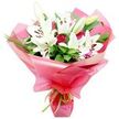 A beautifully hand-tied bouquet of white Oriental lilies and deep red roses is set against a clean white background, highlighting the contrast between the soft petals and vivid colours. At the centre, several large lilies open fully, their pure white, trumpet-shaped petals arching outwards with a graceful curve, showing off dark chocolate-brown anthers perched on slender filaments. Some lilies remain in bud form, their elongated, pale green casings tightly closed, promising future blossoms that will extend the life and changing beauty of the display. Among the lilies, rich red roses are tucked in at different heights and angles, from tightly wound buds with a velvety finish to partially open blooms that begin to reveal their intricate spiral of petals. A lush collar of deep green foliage surrounds the flowers: broad, glossy leaves provide a solid base, while long, slender grass-like blades add a touch of movement and airiness, as if the bouquet had just been gathered from a well-kept garden near New Barnet station. The entire arrangement is wrapped generously in bright pink, slightly translucent cellophane or floral paper, which billows in soft, curved folds around the stems and reflects the light with a subtle sheen, like festive wrapping seen in local shops along the High Road. At the base, a fine lime green ribbon is tied snugly around the stems, creating a neat little bow that adds a fresh accent and echoes the greenery. The mood of the bouquet is warm and celebratory, making it a fitting choice for birthdays, anniversaries, Mother's Day, or offering heartfelt thanks to someone special in the New Barnet area.