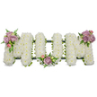 A large, three-dimensional sympathy tribute spells the word MUM in capital letters, each letter densely formed from thousands of small, snow-white chrysanthemums that give the surface a soft, cloud-like texture against a pure, brilliant white backdrop. The chrysanthemums are tightly packed so the letters read clearly from a distance but reveal their fine petal detail up close; the overall glow is quiet and consoling, the white suggesting purity and peaceful remembrance. Three small clusters of soft lavender and pale pink roses are placed as gentle focal points-one nestling on the upper left arm of the first M, another tucked into the inner curve of the U, and a third crowning the upper right arm of the final M-each cluster showing a mix of open blooms and tighter buds with a delicate, powdery rose scent that lifts from the pastel petals. Varied greenery, including slender fern fronds and lighter green filler leaves, peeks between flowers to add depth, contrast and a natural, garden-fresh feel; the foliage also softens the silhouette so the tribute reads as both structured and tender. A dark green supporting frame-likely ribbon-wrapped foam or moss covering-runs along the base and edges, visible as a subtle outline that keeps the letters upright and unified without drawing attention from the blooms. Bathed in soft, diffused light as if set on a chapel or funeral parlour table, the piece conveys calm, respect and intimate remembrance. Crafted with careful florist skill, this MUM tribute is designed for a funeral service, wake or graveside and would be appropriate for families in New Barnet seeking a traditional, heartfelt memorial.