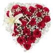 A tender, heart-shaped floral tableau composed of densely clustered deep crimson roses, each rose showing velvety petals at different stages from tight bud to full bloom, sits crisply against a pure white backdrop. Tiny, star-like clusters of white baby's breath (Gypsophila) are woven generously through the roses, their airy, cloud-like texture softening the silhouette and creating luminous pockets of contrast that let the red recede and breathe. In the upper-left curve a single white lily opens with sculptural calm; its broad, pristine petals carry the faintest creamy yellow at the throat and a trio of yellow-orange stamens that punctuate the arrangement with a warm, quiet glow. Soft studio light skims the petals, catching the satin sheen on the rose edges and the waxy smoothness of the lily, while a delicate, romantic scent seems almost to rise from the composition-heady rose perfume balanced by a cleaner, green lift from the lily and gypsophila. The heart is shaped with careful symmetry, the roses forming a lush, textural mass and the baby's breath tracing a halo that makes the form read clearly from any distance. This is an arrangement that reads as both intimate and formal, the kind of bouquet chosen for Valentine's Day, anniversaries, or a deeply felt apology, and it conveys practiced floristry: measured spacing, balanced colour, and considered focal placement. Imagined on a mantel in a New Barnet home after a stroll from Station Road or as a heartfelt delivery to a loved one near Brunswick Park, it speaks of romance, attention, and quiet confidence.