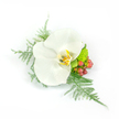 A single, pristine white Phalaenopsis orchid sits at the centre of this compact corsage, its broad, satiny petals opening like a soft architectural bloom against a stark white background. The orchid's throat reveals a whisper of warm yellow and golden tones edged with faint brown markings, lending a quiet depth to the otherwise lunar-white blossom. Around and beneath the flower, feathery sprigs of asparagus fern fan out with delicate, lace-like texture, their pale green threads catching the light and giving the composition a sense of gentle movement as if stirred by a late-morning breeze. To the right, clusters of small, glossy reddish-pink hypericum berries provide a lively, organic punctuation - warm and slightly rustic against the silk-smooth orchid. Nestling beside them is a tight, lime-green chrysanthemum or similar filler bloom, its cushiony surface introducing a fresh, almost zesty green that balances the arrangement and amplifies the feeling of newness.
The design reads as wearable art: asymmetrical but harmoniously balanced, compact enough to be pinned to a lapel or worn as a wrist corsage, composed with the care of a florist who knows how to combine texture, tone and scale. The white backdrop makes every surface-satiny petal, feathery fern, glossy berry-appear crisp and immediate, so a visually impaired client can imagine each tactile contrast. Crafted for occasions that ask for refined understatement-weddings, proms, formal evenings-this piece carries a quiet joy and a fresh scent from the greens. As a New Barnet florist would explain, it captures both modern elegance and a gentle, celebratory warmth suitable for neighbourhood gatherings or a thoughtful gift from local hands.