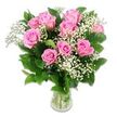 A bright, high-key photograph captures a classic baby-themed bouquet arranged in a clear glass vase, set cleanly against a pure white background that reflects the softness of a New Barnet morning. At the heart of the design, around ten to twelve pink roses gather closely together, their petals forming plush spirals of blush and medium pink, some blooms just unfurling at the edges while others open wide, revealing layered centers like tiny, velvety swirls. Between the roses, delicate stems of baby's breath thread their way, each stem holding clusters of minuscule white flowers that look like droplets of light, creating a feathery halo around the more substantial rose heads. Dark green rose foliage rings the bouquet, the leaves smooth and slightly glossy, offering a cool counterpoint to the warm pink tones and making the colours feel even more vivid. The glass vase is simple and transparent, free of ornament, allowing the viewer to see the straight, green stems gathered in clear, fresh water that suggests the flowers were recently prepared, perhaps for same-day delivery to new parents near Hadley Wood or a baby shower hosted close to New Barnet's quiet residential streets. Soft, even lighting eliminates harsh shadows, so every petal edge and tiny white blossom is tenderly defined without looking stark. The overall shape of the bouquet is round and full, with a gentle, embracing quality that mirrors the emotions of cuddling a newborn. It is a visually serene yet joyful composition, perfectly suited to celebrating new arrivals, early birthdays, or any sweet milestone in a young family's life in and around New Barnet.