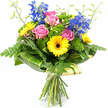 A vivid mixed bouquet is shown standing upright against a pure white background, its colours glowing as if freshly arranged in a New Barnet flower shop on a bright morning. At the centre, several pink roses with gently unfurling petals form a romantic core, their soft, velvety texture and layered spirals bringing a sense of tenderness and affection. Surrounding them, yellow gerbera daisies with dark brown centres face outward confidently, their wide, open petals creating a sunlit effect that conveys happiness and positivity, ideal for a birthday greeting, exam congratulations, or a cheerful pick-me-up for someone living near Victoria Park or along Lyonsdown Road. Tall stems of vivid blue delphiniums rise above the more rounded forms, their small, closely packed florets adding cool, vertical accents that echo the clear, crisp tones of a spring sky over New Barnet.   

The entire arrangement is cushioned and framed by lush greenery. Fine, feathery fern fronds spill from the sides, giving the bouquet a soft, somewhat whimsical outline, as though it has been gathered straight from a well-tended garden. Interspersed between the flowers are clusters of bright green, textured filler foliage that provide depth, volume, and a pleasing contrast to the smoother petals of the roses and gerberas. Larger, glossy dark green leaves, some sporting subtle lighter streaks, are skillfully curled and wrapped around the lower section of the blooms, forming a structured green collar that anchors the design and shows off the florist's expert hand. Above the main flowers, slim, pale green stems tipped with tiny buds reach gently upward, introducing a sense of movement and new growth.   

At the bottom of the image, the natural stems are gathered neatly and bound with a simple, natural-coloured ribbon or twine, making it clear that this is a hand-tied bouquet, ready for delivery across New Barnet. The composition as a whole radiates joy, freshness, and thoughtful care, like a personal message expressed in petals and leaves, captured in a single vibrant photograph.