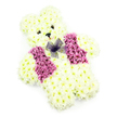 This image shows an exquisitely detailed teddy bear created entirely from fresh flowers, presented against a simple white background that allows every feature to be clearly seen. The bear's body is built with tightly clustered, creamy white chrysanthemums, their layered petals giving the impression of soft, brushed fur from the top of the rounded head down to the solid little paws. The florist has sculpted the ears, arms, and legs so they appear plump and cuddly, adding to the sense of tenderness the tribute conveys. Two small, dark eyes and a compact black nose sit neatly in the centre of the face, bringing character and an almost protective warmth to the expression. A gentle suggestion of a smile curves under the nose, hinting at comfort and reassurance. In contrast to the pale floral fur, the bear wears a vivid waistcoat made from deep pink and lilac-toned blooms that cover the front of the torso, adding a loving burst of colour that feels both joyful and respectful. At the bear's neckline, a tiny bow fashioned from translucent purple netting introduces a final, refined flourish, as though the bear is dressed specially for a meaningful occasion in or around New Barnet, perhaps for a service at a local church or crematorium. The overall mood is one of quiet affection and remembrance, suitable for a child's funeral, a memorial for a much-loved grandchild, or a tender tribute delivered to a family home near Oakhill Park, offering a soft, floral symbol of love and comfort during a difficult time.